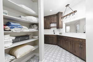 Kitchen with dark brown cabinetry, backsplash, recessed lighting, light stone countertops, and light floors