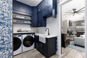 Laundry area featuring light wood-type flooring, ceiling fan, and cabinet space