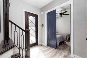 Entryway featuring light wood-style flooring, ceiling fan, and stairway
