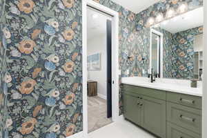Bathroom with vanity, light tile patterned floors, and wallpapered walls