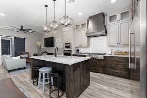 Kitchen featuring a barn door, ceiling fan, an island with sink, dark brown cabinetry, and recessed lighting