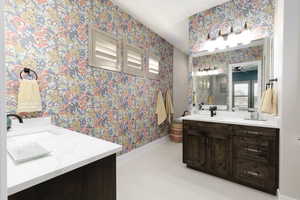 Full bathroom featuring two vanities, wallpapered walls, and light tile patterned floors
