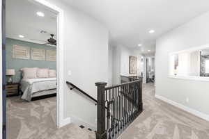 Hall with an upstairs landing, light colored carpet, recessed lighting, and wallpapered walls