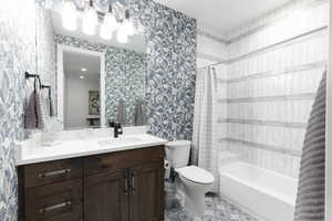 Full bath with wallpapered walls, shower / bath combo, and vanity