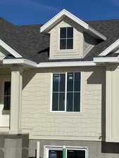 View of side of home with roof with shingles