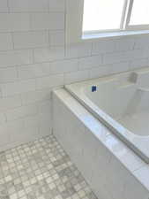 Full bath featuring a garden tub and tile walls
