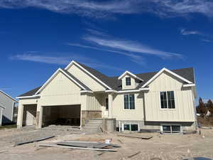 View of front facade featuring board and batten siding and roof with shingles