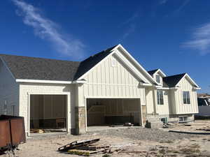 View of front of house with board and batten siding, a shingled roof, and a garage