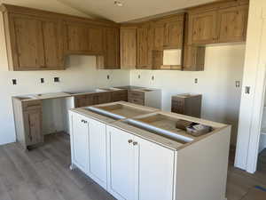 Kitchen featuring light wood-style floors, a textured ceiling, brown cabinets, electric cooktop, and a kitchen island