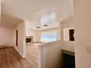 Unfurnished living room featuring wood finished floors, a textured ceiling, and a fireplace