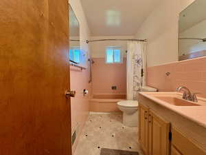 Bathroom with vanity, tile walls, and shower / bathtub combination with curtain