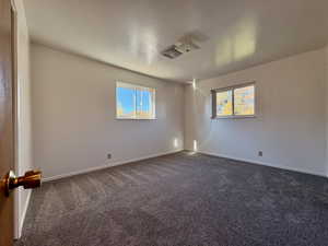 Unfurnished room featuring dark carpet and baseboards