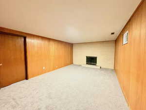 Unfurnished living room featuring wood walls, carpet flooring, and a fireplace