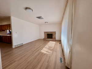 Unfurnished living room with light wood finished floors and a stone fireplace