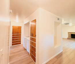 Corridor featuring light wood-type flooring, separate washer and dryer, and stairway