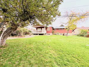View of green lawn featuring a deck