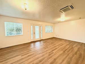 Unfurnished room featuring cooling unit, a textured ceiling, and light wood-style floors