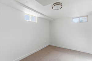 Basement with light colored carpet and a textured ceiling