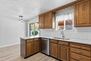 Kitchen with backsplash, a peninsula, light wood-type flooring, brown cabinets, and a textured ceiling