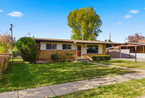 Single story home featuring brick siding, a gate, an attached carport, and driveway