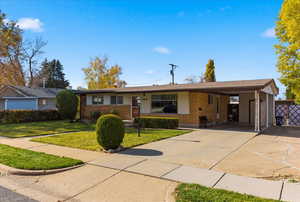 Single story home with brick siding, a front lawn, an attached carport, concrete driveway, and roof with shingles