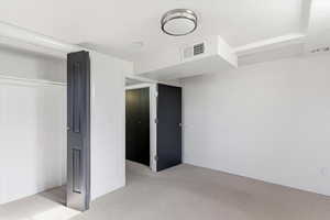 Unfurnished bedroom with light carpet and a closet