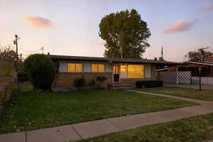 View of front of property with brick siding, a carport, a gate, and driveway