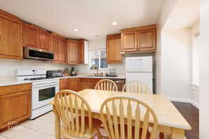 Kitchen with light countertops, appliances with stainless steel finishes, brown cabinets, and recessed lighting