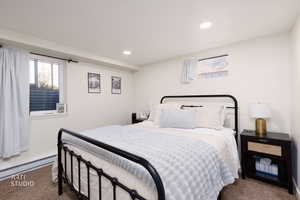 Carpeted bedroom with multiple windows, recessed lighting, and baseboard heating