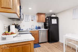 Kitchen featuring light countertops, brown cabinetry, stainless steel appliances, light wood-type flooring, and recessed lighting