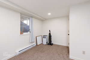 Spare room featuring a baseboard heating unit, light carpet, and recessed lighting