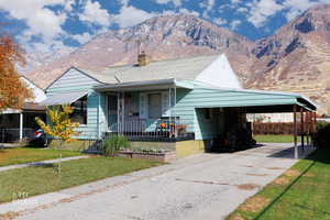 Bungalow-style home with covered porch, an attached carport, a mountain view, a chimney, and concrete driveway