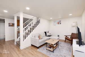 Living room featuring light wood-style flooring, recessed lighting, and stairway