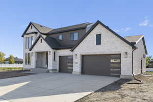 View of front facade with concrete driveway, a shingled roof, an attached garage, and brick siding