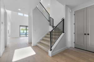 Entryway with light wood-style floors, recessed lighting, a towering ceiling, and stairs