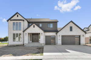 View of front of house featuring driveway, a shingled roof, brick siding, and an attached garage