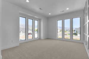 Empty room with light colored carpet, recessed lighting, a residential view, and a mountain view