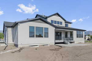 Back of house featuring stone siding, stucco siding, a mountain view, and a porch