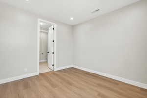 Empty room with light wood finished floors and recessed lighting