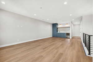 Unfurnished living room with light wood-style floors, recessed lighting, wet bar, and wine cooler