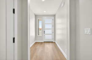 Doorway to outside with wood finished floors and recessed lighting