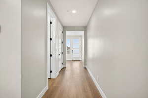 Hallway with light wood-style floors and recessed lighting