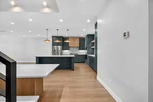 Kitchen with decorative backsplash, decorative light fixtures, light wood-type flooring, high quality fridge, and recessed lighting