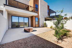 Back of property with stucco siding, a patio, a balcony, and a fire pit