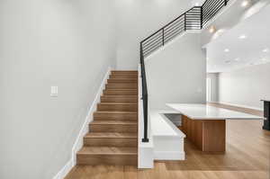 Staircase featuring wood finished floors and recessed lighting