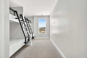 Hall featuring light colored carpet and baseboards