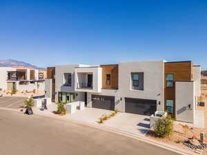 Modern home featuring stucco siding, concrete driveway, a garage, and a mountain view