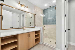 Bathroom with a shower stall, vanity, light tile patterned floors, and recessed lighting