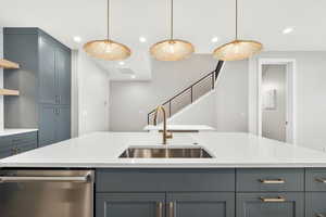 Kitchen featuring gray cabinetry, stainless steel dishwasher, light stone counters, and recessed lighting