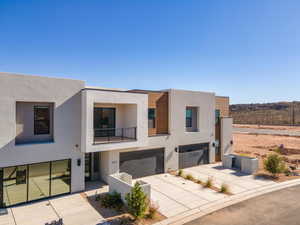 Contemporary house with a balcony, driveway, stucco siding, and an attached garage